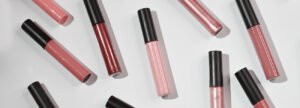 A photo showcasing Radical Cosmetics' luxurious lip gloss collection, featuring a radiant lineup of high-shine shades including sheer nude, soft pink, warm coral, shimmering rose gold, and deep berry. Each gloss is presented in sleek, clear tubes with elegant black caps, allowing the vibrant, hydrating colors to shine through. These clean beauty lip glosses are formulated with nourishing natural oils and botanicals for a non-sticky, moisturizing finish. Ideal for all skin tones, this cruelty-free, vegan, paraben-free lip gloss range delivers rich pigment, long-lasting wear, and a glossy finish. Perfect for beauty brands seeking private label or contract manufacturing of eco-conscious, high-performance color cosmetics.