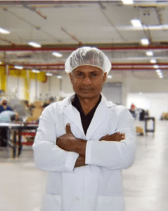 Fenton Baijnath, Founder & CEO of Radical Cosmetics, standing confidently in the company's modern, sleek office. Fenton is dressed in a sharp business suit, exuding professionalism and leadership. The background features a clean, minimalist design with the Radical Cosmetics logo subtly visible on the wall. The lighting is bright and professional, showcasing a polished environment that reflects the company’s commitment to high-quality beauty products. Fenton’s focused expression emphasizes his dedication to innovation and sustainable practices within the cosmetics industry. Radical Cosmetics is known for its expertise in clean beauty, offering high-performance, non-toxic, cruelty-free, and ethically sourced cosmetic and skincare solutions. The photo highlights the leadership behind the brand, focused on providing transparent, effective products with a commitment to sustainability and clean ingredients.