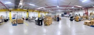 Panoramic view of Radical Cosmetics' state-of-the-art cosmetics manufacturing facility in the USA, showcasing an organized production line, packaging stations, and high-quality cosmetic product assembly. Leading private-label cosmetics manufacturer specializing in natural and organic beauty solutions.