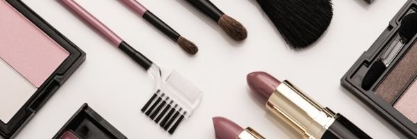 Flat lay of blank cosmetic packaging, including jars, tubes, and compacts, representing unbranded beauty products ready for custom logo printing.