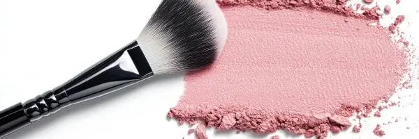 Flat lay of assorted cosmetics, including lipsticks, eyeshadows, and skincare products, arranged aesthetically on a neutral background.