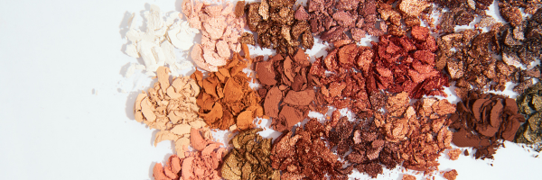 Modern makeup flat lay featuring foundation, mascara, lipstick, eyeliner, blush, and concealer products from luxury and drugstore beauty brands